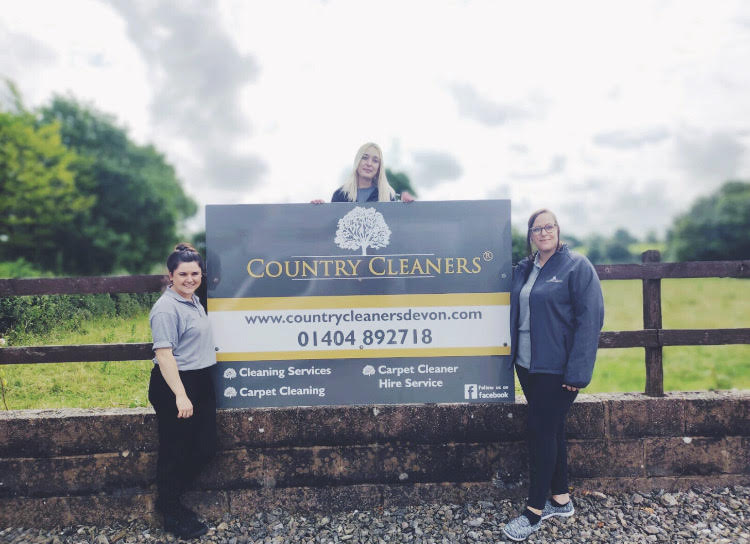 Country Cleaners team standing by Country Cleaners Billboard